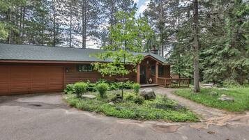 A cabin with a garage, a porch, and a garden area.