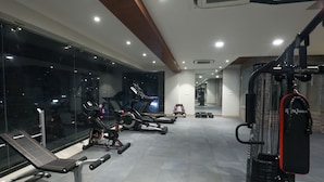 Ein modernes Fitnessstudio mit verschiedenen Trainingsgeräten, darunter Laufbänder, eine Hantelbank und Kurzhanteln.