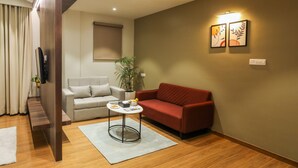 Ein modernes Wohnzimmer mit einem roten Sofa, einem weißen Sessel, einem kleinen Couchtisch und einer Topfpflanze.