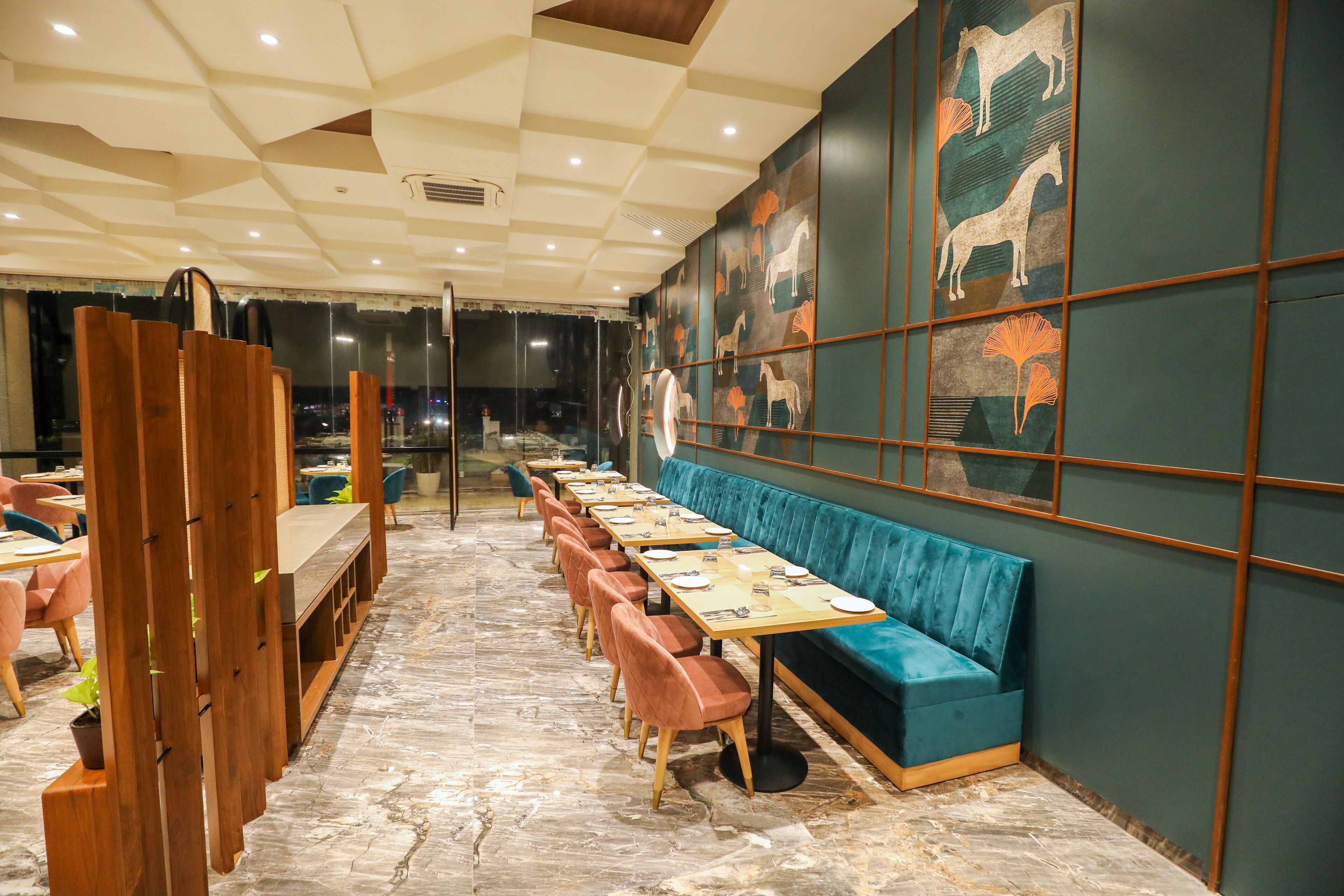 Un restaurante con una barra larga, asientos acolchados azules y decoración de caballos en las paredes.