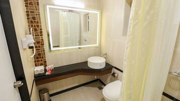 A bathroom with a white sink, a mirror with lights, a toilet, and a shower curtain.