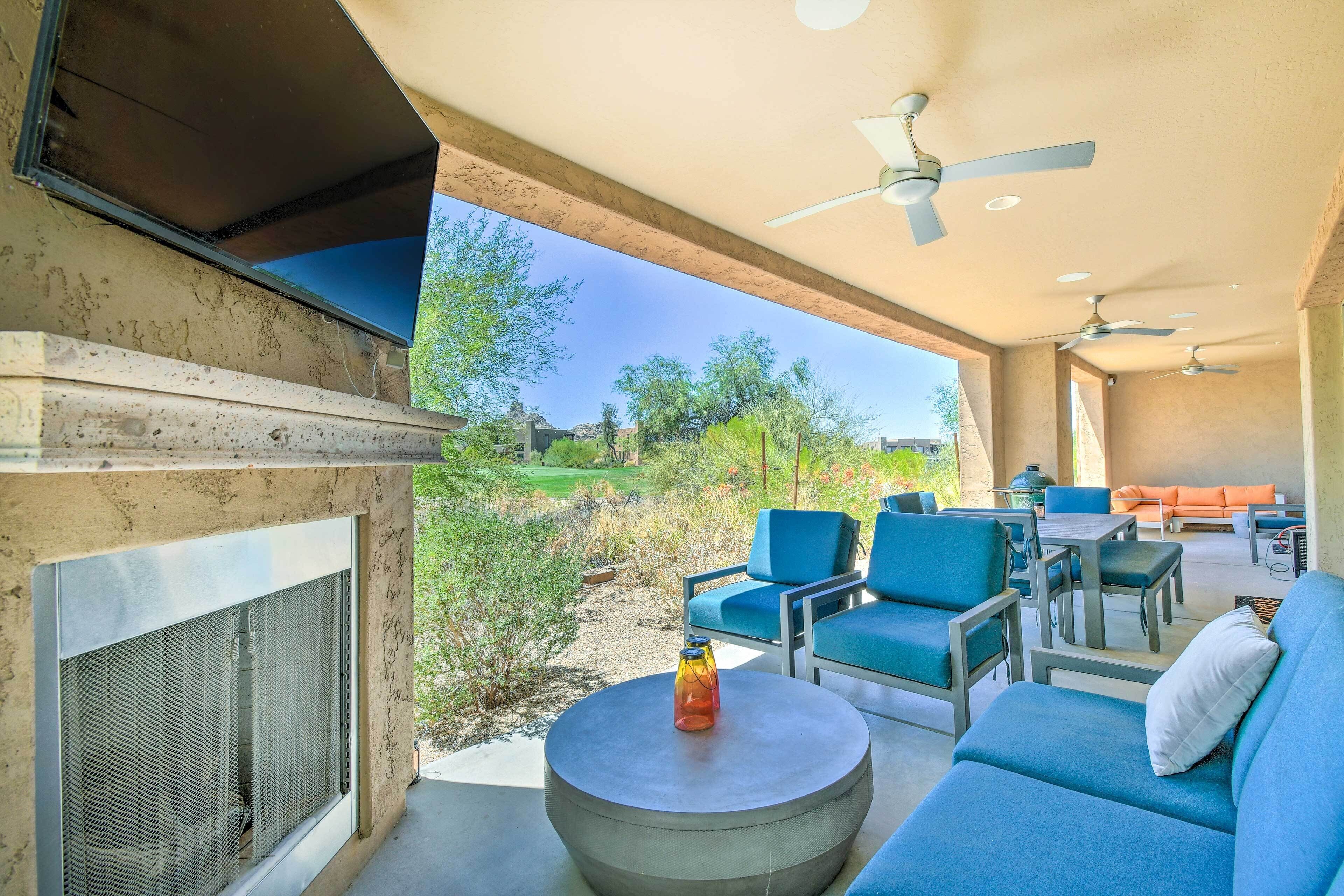 An outdoor patio with a grill, blue seating, and ceiling fans.