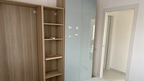 A bedroom with a wooden wardrobe, a bed with a white bedspread, and a light blue wardrobe.