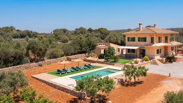 Una villa de estilo mediterráneo con piscina, porche cubierto y jardín ajardinado.