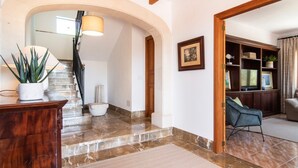 Un amplio salón con una escalera, un mueble de madera y un televisor.