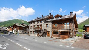 Un bâtiment en bois à plusieurs étages, doté de balcons, d’un escalier et offrant une vue dégagée sur les montagnes environnantes.