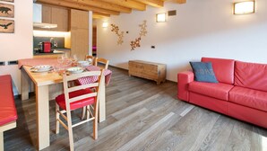 Un coin repas avec une table en bois, des chaises et un canapé rouge.