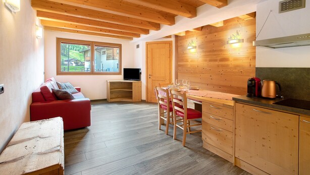 Une cuisine de taille réduite, avec des meubles de rangement en bois, une table à manger et un canapé rouge.