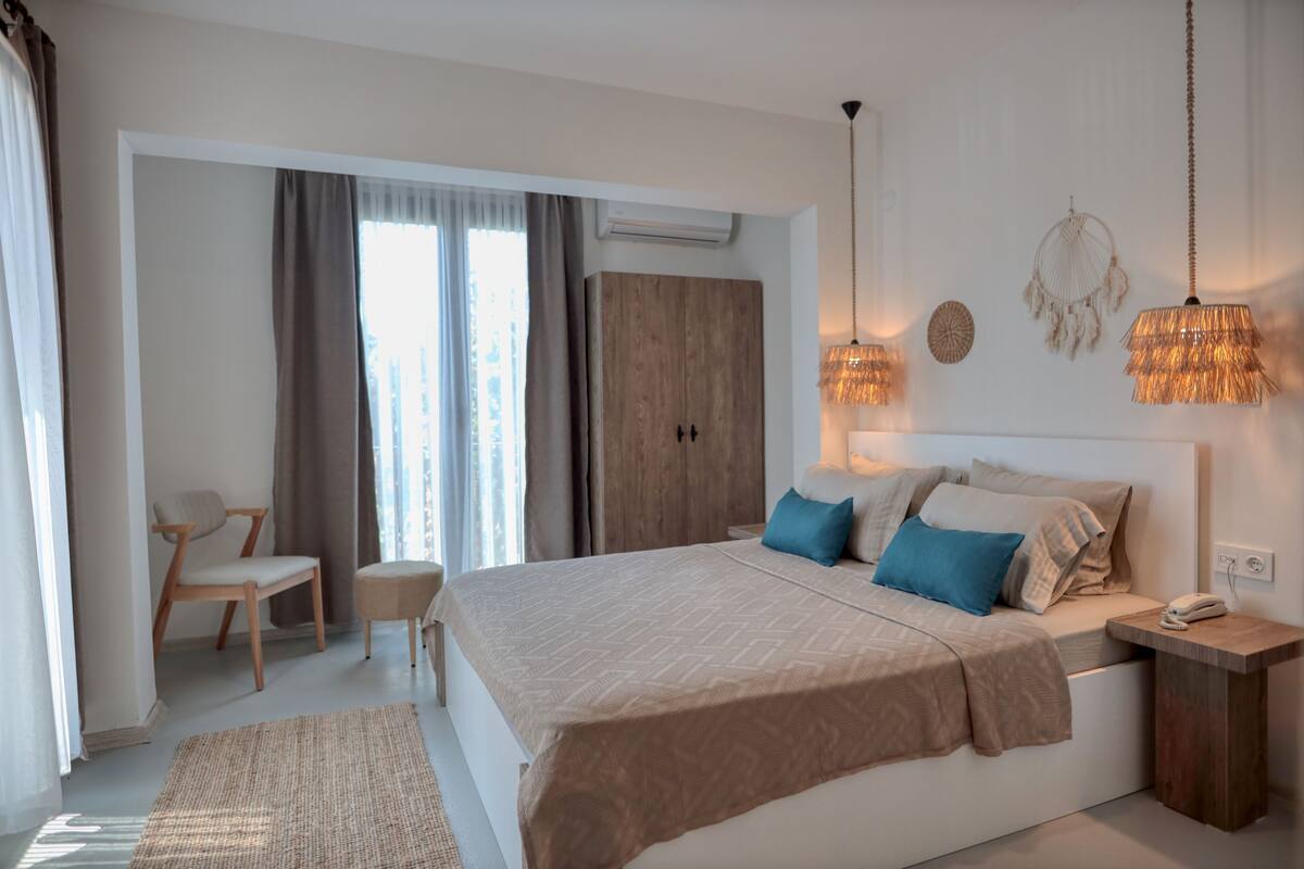 A modern bedroom with a large bed, a wooden wardrobe, a desk, and a chair.