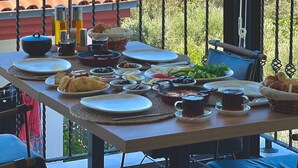 Mesa en balcón con diversos platos y vista a un pueblo costero.