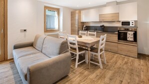 Une cuisine moderne avec un coin repas, un plancher en bois et un four encastré.