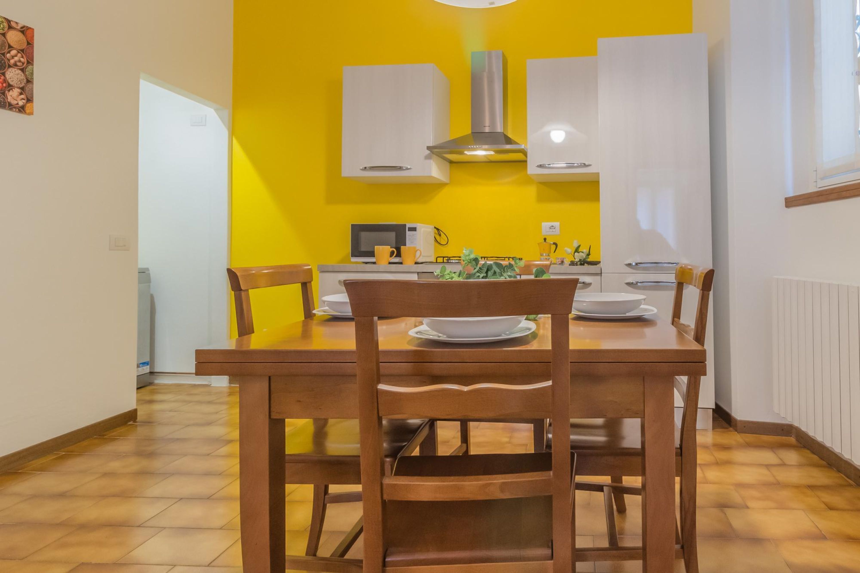 A dining area with a wooden table and chairs, a microwave, and white cabinets.