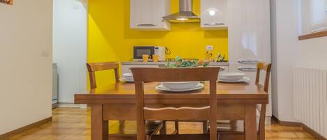 A dining area with a wooden table and chairs, a microwave, and white cabinets.