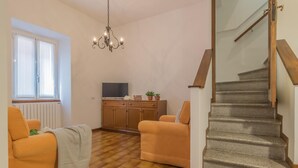 A living room with a sofa, a TV, a wooden cabinet, and a staircase. - Casa Greppi Varenna in Varenna (Varenna)