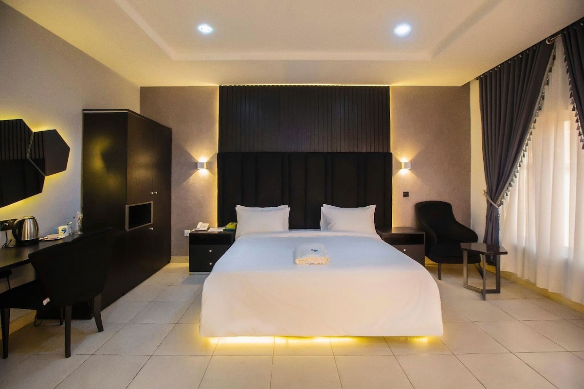 A hotel room with a large bed, bedside tables, a desk, and a chair.