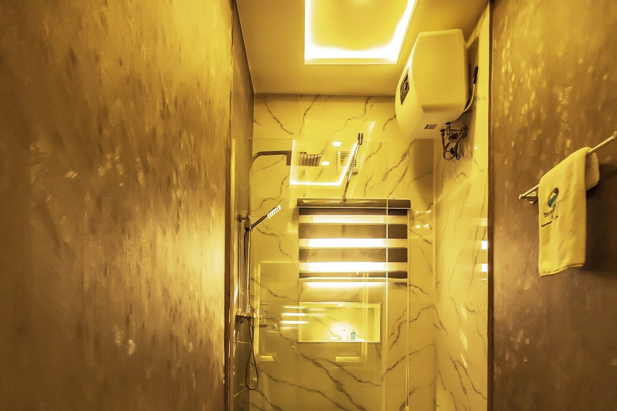 A modern bathroom with a toilet, shower, and marble walls.