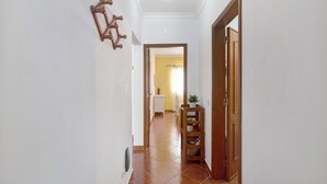 A hallway with a wooden door, a wall-mounted rack, and a tiled floor. - Apartment 'Algarvio Ao Sol' with Balcony, Wi-Fi and Air Conditioning (Conceição de Tavira)