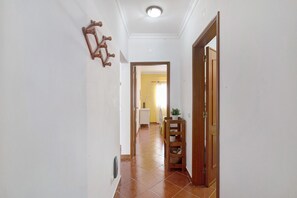 A hallway with a wooden door, a wall-mounted rack, and a tiled floor.