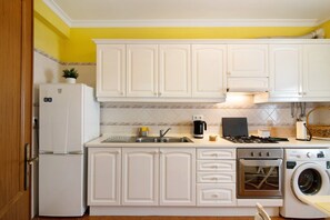A kitchen with white cabinets, a refrigerator, a sink, a stove, a washing machine, and a dishwasher.