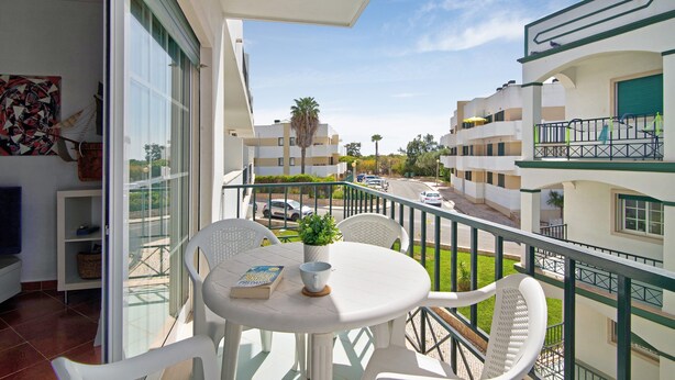 A balcony with a table, chairs, a potted plant, and a book. - Apartment 'Algarvio Ao Sol' with Balcony, Wi-Fi and Air Conditioning (Conceição de Tavira)
