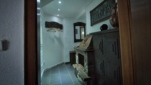 Un pasillo con chimenea de piedra, un espejo y un armario de madera.