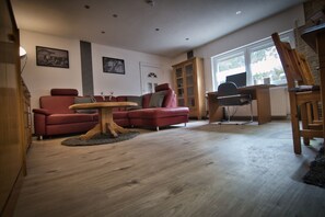 Una sala de estar con un sofá rojo, una mesa de centro de madera y un aparador de madera.