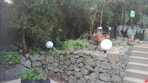Una pared de piedra con una jardinera negra y objetos esféricos blancos encima.