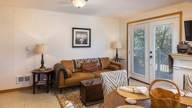 A living room with a sofa, coffee table, and a fireplace. There is a framed picture on the wall and a door leading outside. - Ramblin Rose, Apartment in Central Area, Sleeps 4 (Sequim)