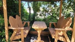 A wooden Adirondack chair and table set under a pergola in a garden. - Ramblin Rose, Apartment in Central Area, Sleeps 4 (Sequim)