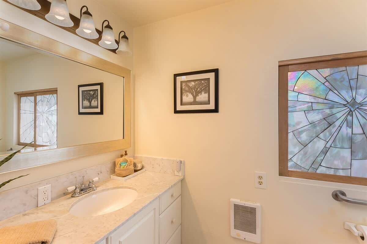 A bathroom with a sink, mirror, and framed pictures on the wall.