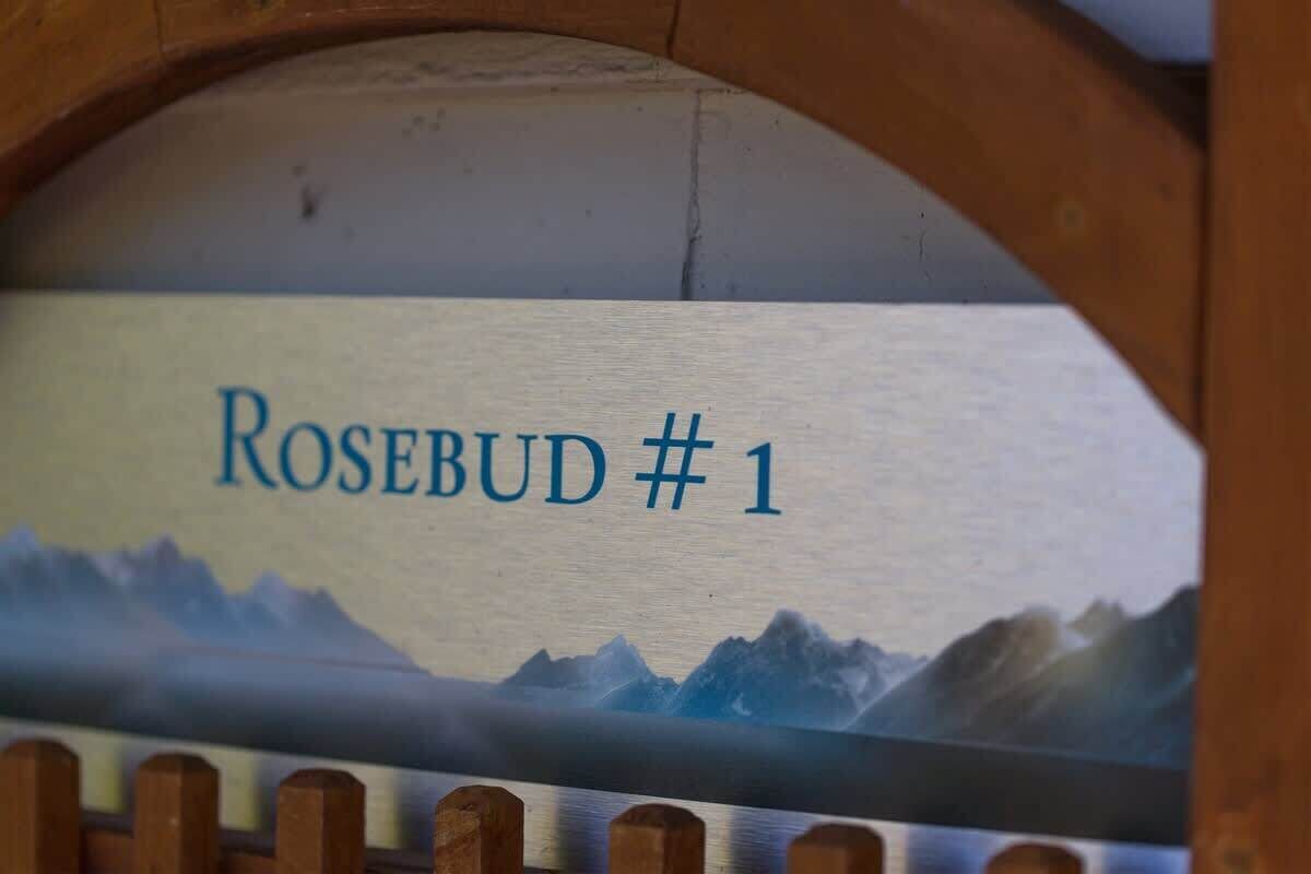A wooden sign with the text "Rosebud #1" and a mountain landscape.