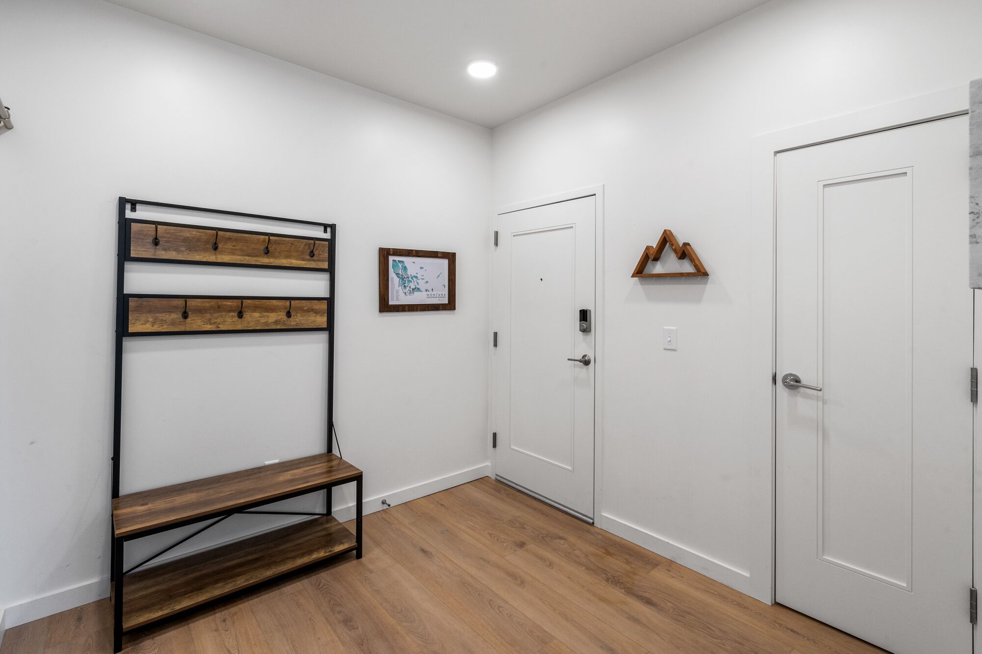 Un pasillo con un banco de madera, un perchero de pared y un mapa enmarcado.