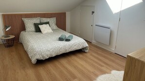 A bedroom with a skylight, a bed with patterned bedding, a bedside table, and a radiator. - Grand Appartement Terrasse Hypercentre (Poitiers)