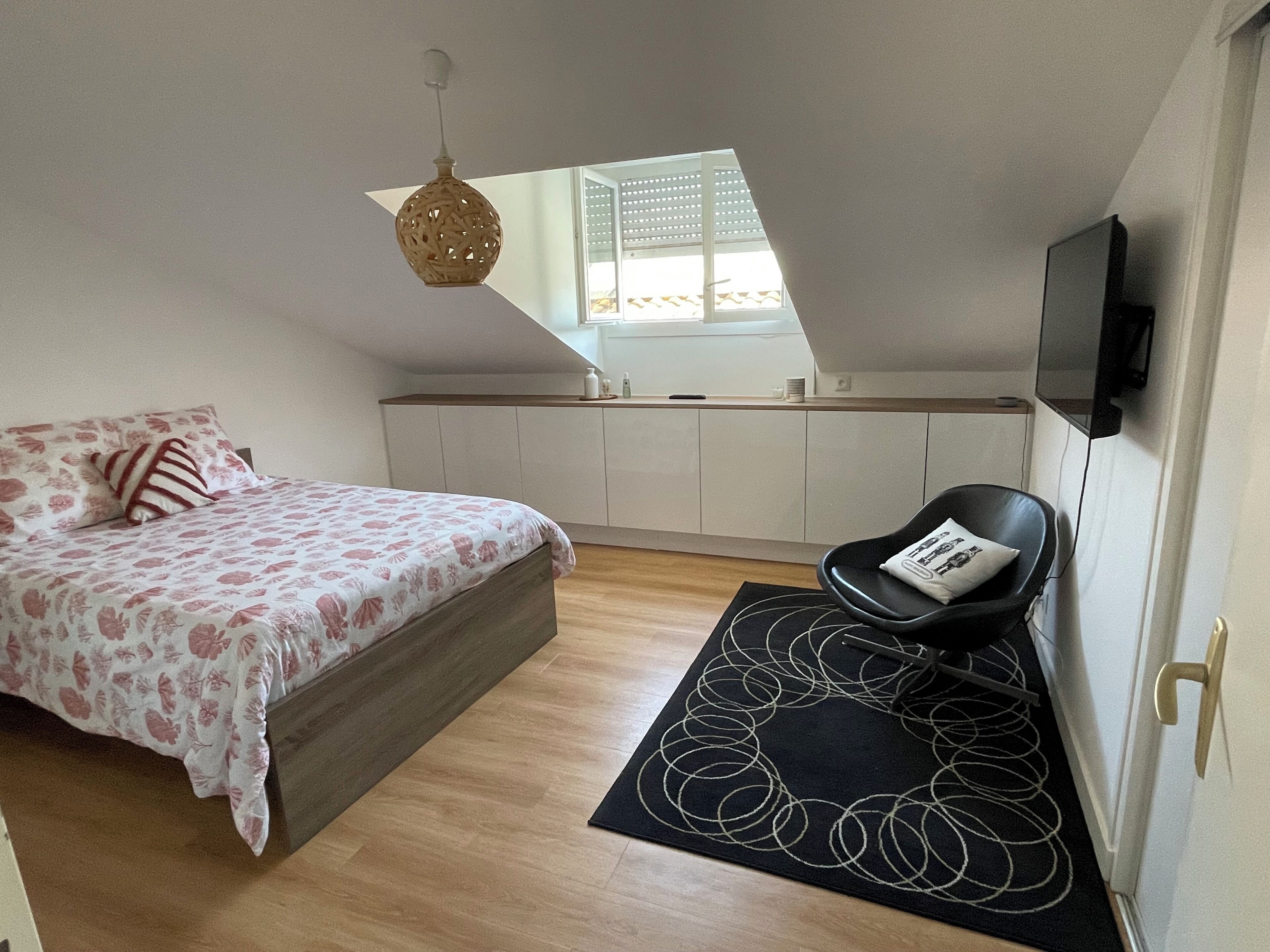 Une chambre à coucher avec un lit, une chaise, une fenêtre et un téléviseur.
