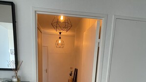 A hallway with a wooden floor, a desk with a lamp, and a door on the right. - Grand Appartement Terrasse Hypercentre (Poitiers)