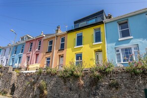 A row of colorful terraced houses with stone walls and flower boxes.