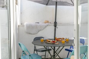 A dining area with a table set for two, a white furry object on the wall, and a metal umbrella.