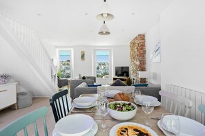 A dining area with a table set for a meal, a sofa, and a TV in the background.