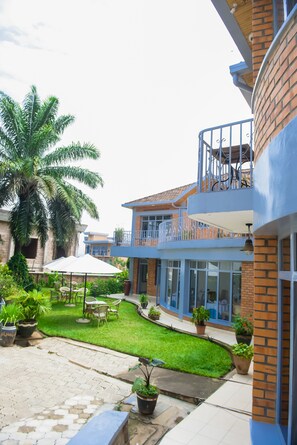 A two-story building with a balcony, outdoor seating area, and potted plants. - ONE CLICK HOTEL (Kigali)
