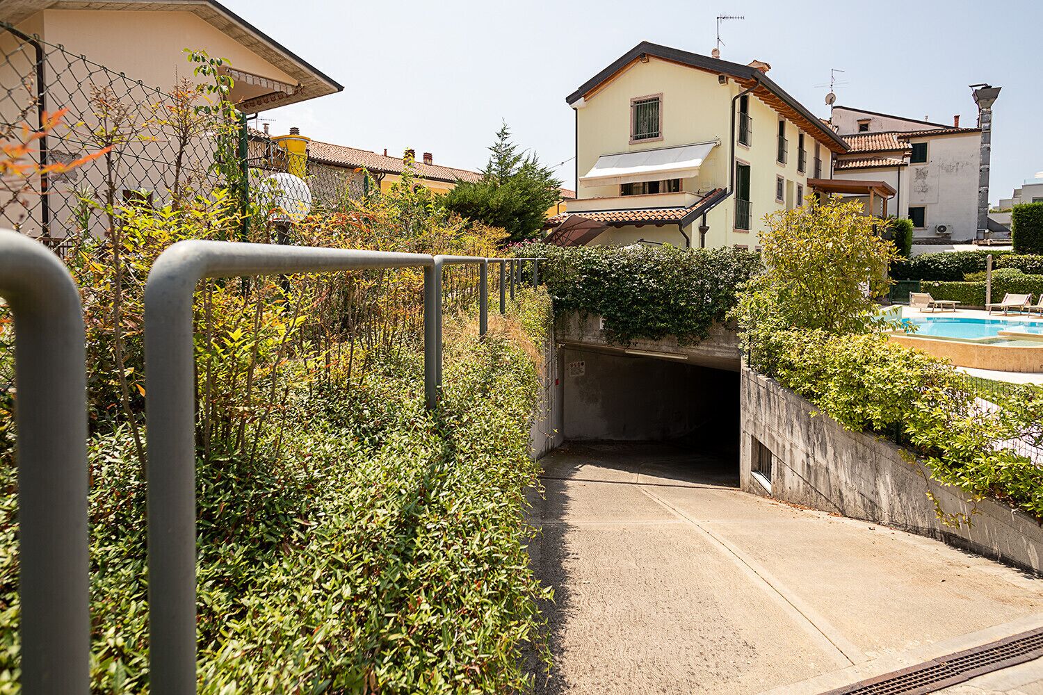 A residential area with a tunnel entrance, a swimming pool, and a house with a tiled roof.
