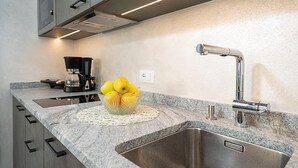 Een keuken met granieten aanrecht, een roestvrijstalen spoelbak en een schaal appels op een kantbordje.