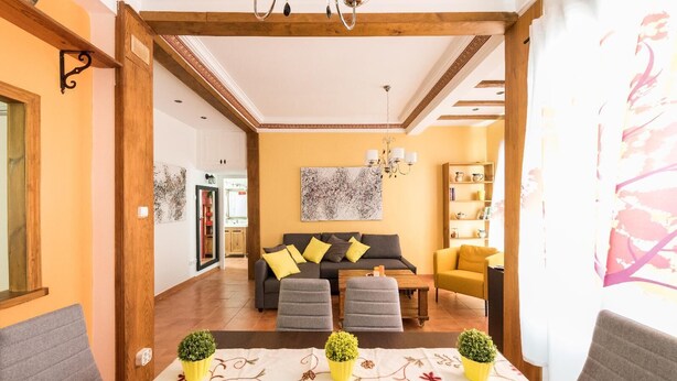 Een moderne woonkamer met een bank, salontafel en gele fauteuils. Op de salontafel staan potten met planten.