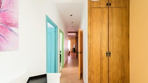 Een hal met een houten garderobe, een blauwe deur en een witte muur met een afbeelding.
