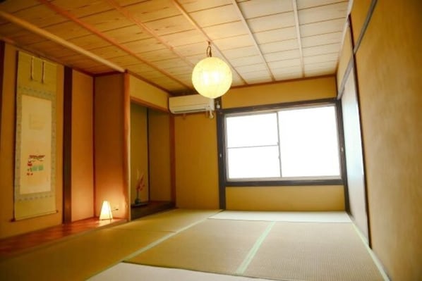 A traditional Japanese room with tatami flooring, a shoji screen, and a hanging paper lantern.
