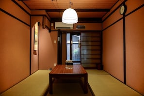 Relax in a serene space with a tatami floor, wooden table, and a glass vase, perfect for dining or unwinding.