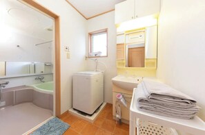 Ein Badezimmer mit einer Badewanne, einem kleinen Heizkörper, einem Waschbecken und einem Spiegel.
