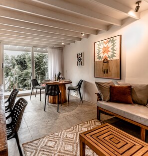 Ein modernes Wohnzimmer mit einem runden Holztisch, zwei Stühlen, einer Couch und einem Teppich.