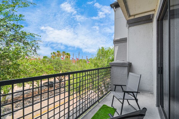 Enjoy the serene view from this balcony with a seating area and table.