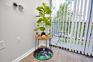 Relax in a serene space with a leafy green plant, a balcony view, and comfortable seating.