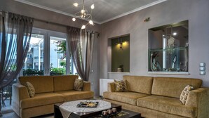 Sala de estar com dois sofás, uma mesa de centro e uma grande janela com cortinas.